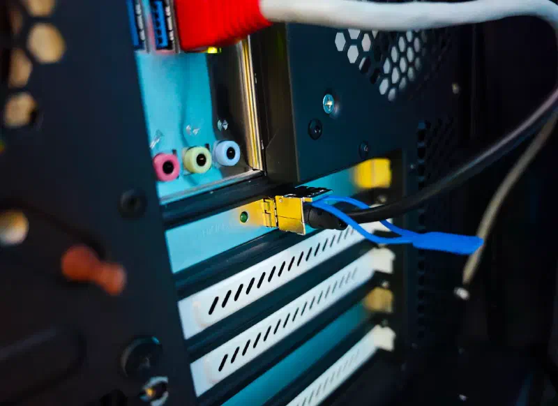 A MikroTik DAC end seated in an SFP+ cage, blue pull tab and link LED visible