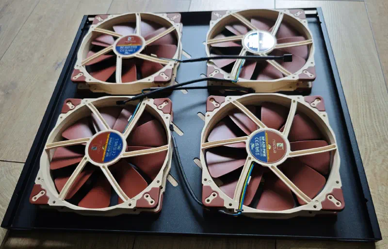 Four 200 mm Noctua NF-A20 fans laid on the drilled rack shelf before installation